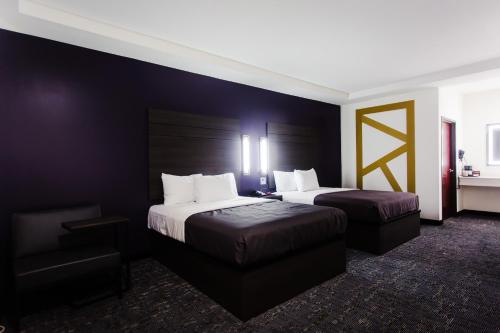 a hotel room with two beds and a chair at Palacio Royale Inn Boutique Katy in Katy
