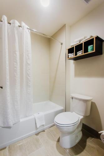 a bathroom with a white toilet and a bath tub at Palacio Royale Inn Boutique Katy in Katy