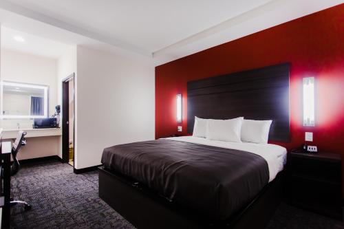 a bedroom with a large bed with a red wall at Palacio Royale Inn Boutique Katy in Katy