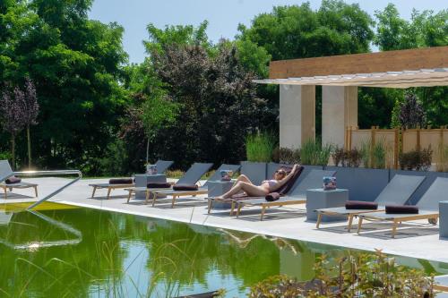 a woman sitting in a chair next to a pool at Ana Hotels Europa Eforie Nord in Eforie Nord