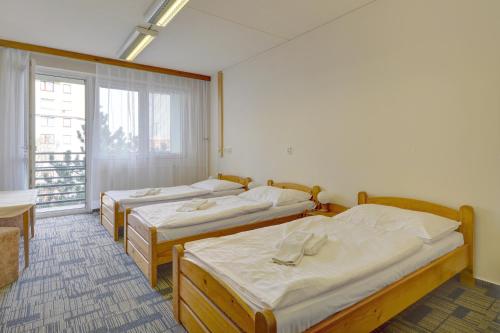 three beds in a room with a window at Volha in Prague