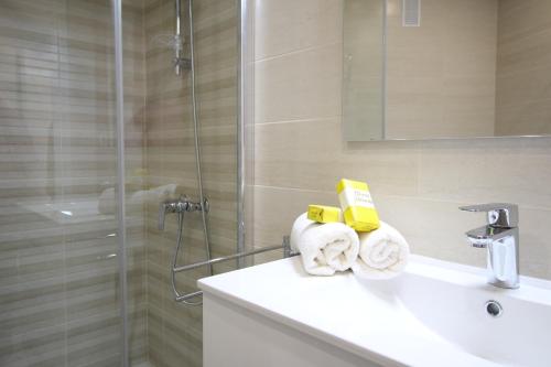 a bathroom with a shower and a sink with towels at Del Parque Flats - Zamarrilla in Málaga