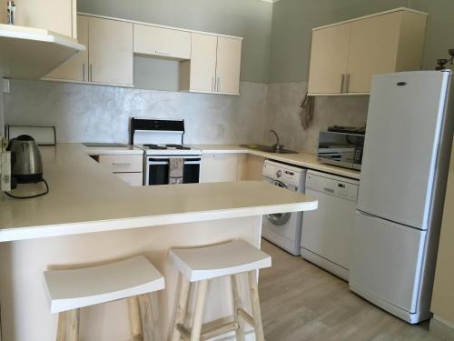 Una cocina con gabinetes blancos y un refrigerador blanco. en Ocean view, Swakopmund, 3-bedroomed apartment, en Swakopmund