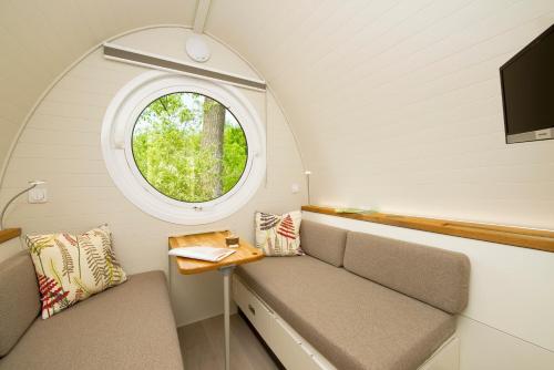 een kleine kamer met een raam en een bank bij Glamping Resort Biosphäre Bliesgau in Kleinblittersdorf