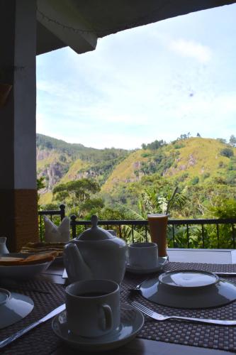 Una mesa con tazas y platillos con vista a una montaña. en Rock side inn - Ella, en Ella