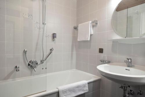 een badkamer met een bad, een wastafel en een douche bij Hotel Neue Burg in Nauders