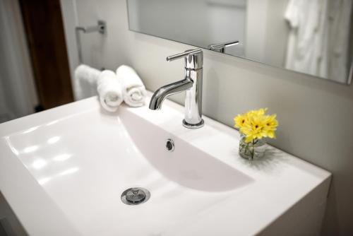 a bathroom sink with a vase of flowers on it at The Kitch'inn - Boutique Inn and Wine Bar in Mahone Bay