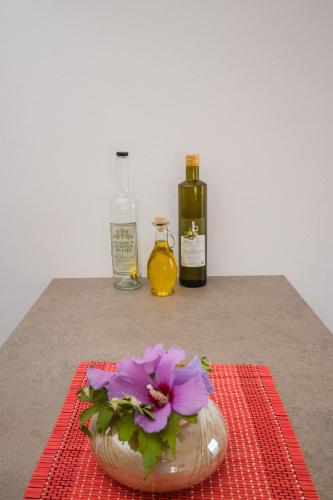 a flower in a bowl on a table with two bottles at Apartments Val Maslina in Utjeha