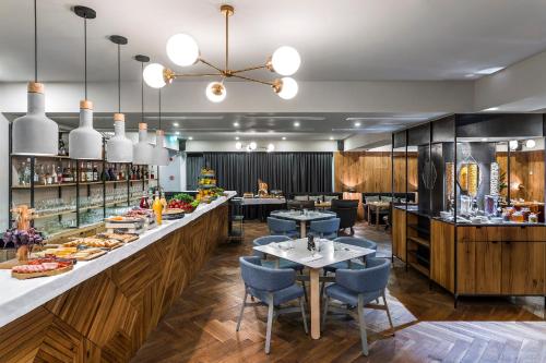 a restaurant with a long counter with tables and chairs at Shota @ Rustaveli Boutique Hotel in Tbilisi City