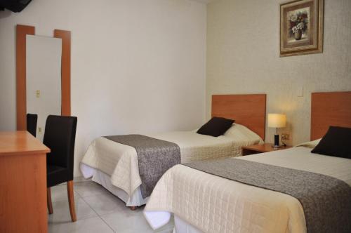 a hotel room with two beds and a desk at Pequeno Gran Hotel in Aguascalientes