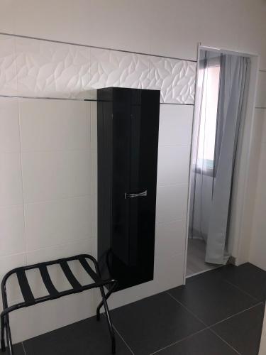 a black cabinet in a white room with a chair at Chambre d'hôtes les Iris à Mios sur le Bassin d'Arcachon in Mios