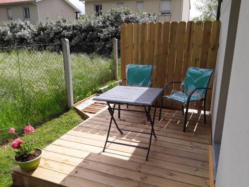 a patio with two chairs and a table on a deck at Chambre d'hôtes les Iris à Mios sur le Bassin d'Arcachon in Mios