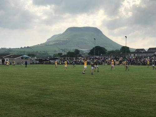 a group of people playing soccer on a field with a mountain at Ballymacdoe Cottage Cushendall in Cushendall