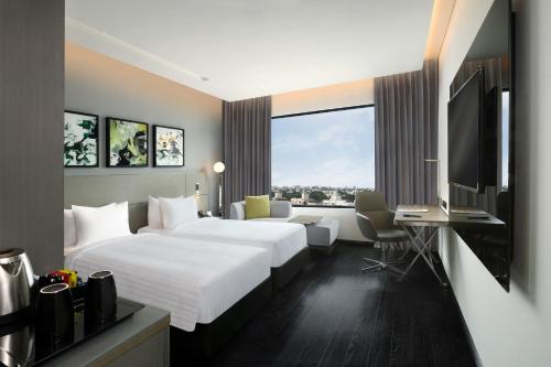 a hotel room with a bed and a desk and a tv at Novotel Chennai Chamiers Road in Chennai