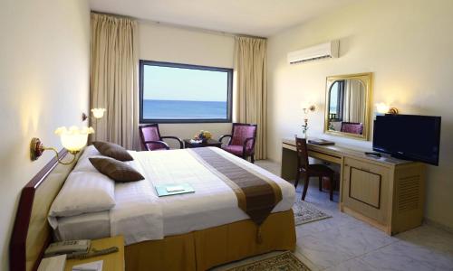 a hotel room with a bed and a desk and a television at Resort Sur Beach Holiday in Sur