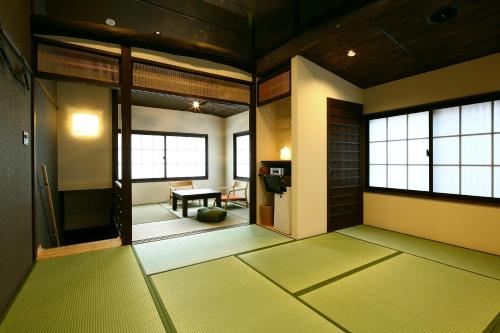 a japanese room with green floors and windows at Machiya Kaemon in Kyoto