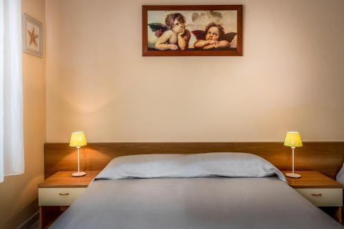 a bedroom with a bed with two lamps and a picture on the wall at Residence Daniele in Bellaria-Igea Marina