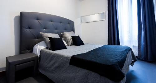 a bedroom with a large bed with a large headboard at Hotel Europe BLV in Paris