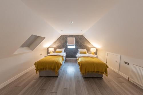 a attic bedroom with two beds with yellow blankets at Ivory Lodge in Reading