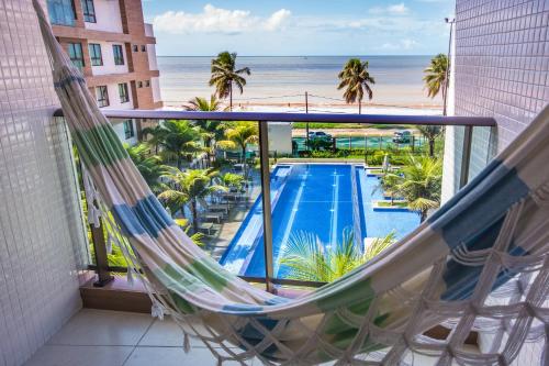 a hammock on a balcony with a view of the ocean at Luxor Paulo Miranda Home Service in João Pessoa