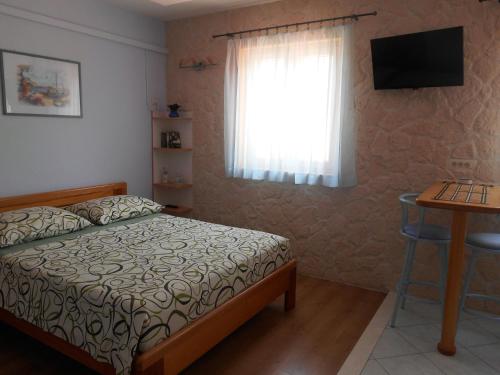 1 dormitorio con cama, ventana y mesa en Apartments Brešan, en Trogir