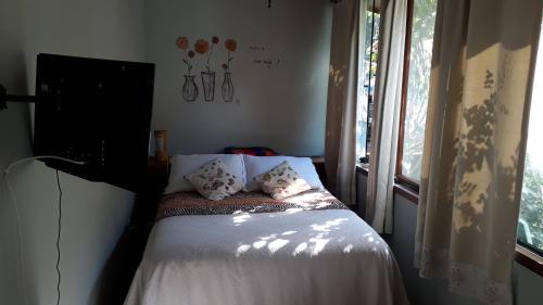 a bedroom with a bed with pillows and a window at Be Hospedagem in Lumiar