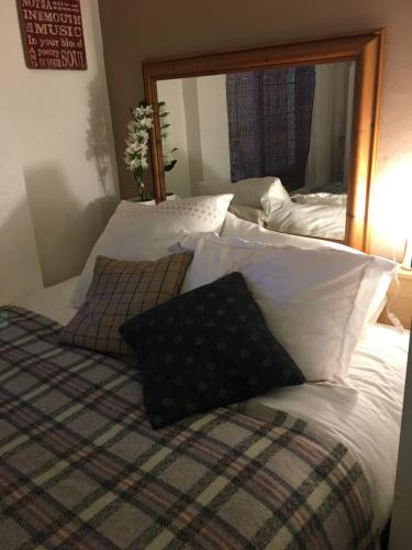 a bed with white pillows and a large mirror at Wynberg House Bed & Breakfast Swansea in Swansea