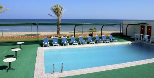 una piscina con sillas y la playa en Resort Sur Beach Holiday, en Sur