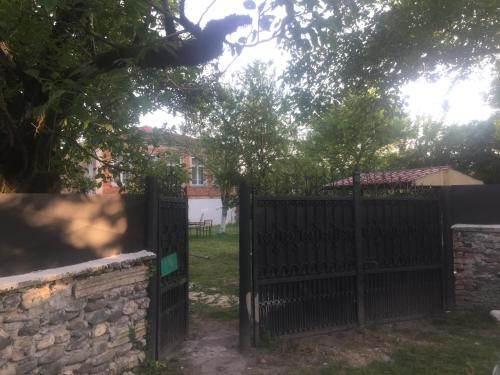 a black fence with a stone wall and trees at Lazuri Keria Family Guesthouse in Khoni