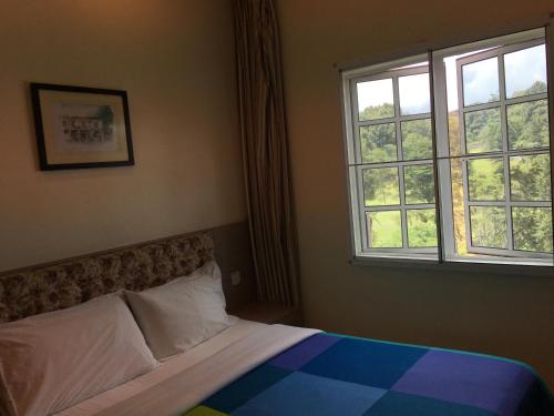a bedroom with a bed and a window at CH Green Stay Resort Apartment in Cameron Highlands