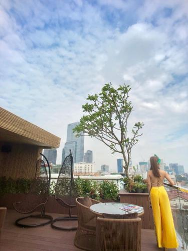 a woman in a yellow dress standing on a balcony at Adora Hotel in Ho Chi Minh City