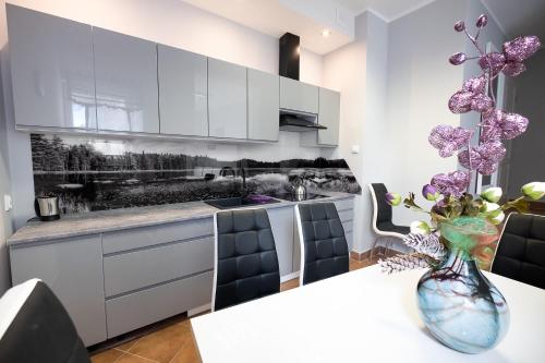 a kitchen with white cabinets and a table with a vase at Apartament Augustów in Augustów