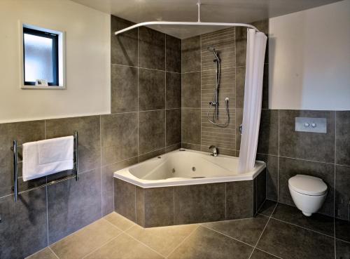 a bathroom with a bath tub and a toilet at The St James Premium Accommodation in Hanmer Springs