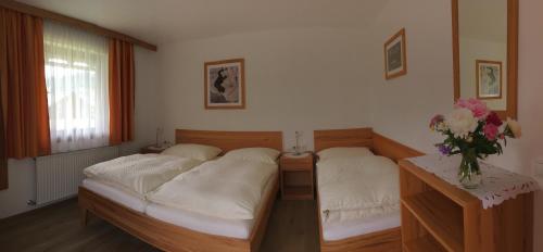 a bedroom with two beds and a vase of flowers at Ferienwohnungen Passrugger in Eben im Pongau