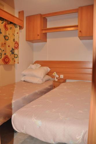 une petite chambre avec deux lits et une fenêtre dans l'établissement Mobil-home 221 Sigean, à Sigean