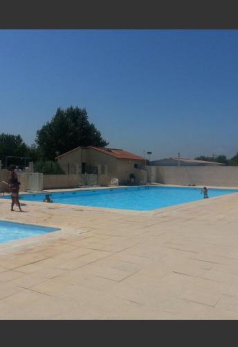 Une grande piscine bleue avec des personnes se promènent autour de celle-ci. dans l'établissement Mobil-home 221 Sigean, à Sigean