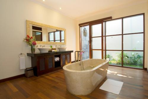 a bathroom with a tub and a sink and a mirror at Ellora Villa in Sanur