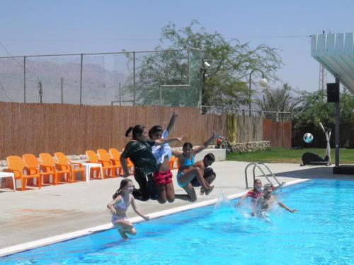 a group of people jumping into a swimming pool at Elifaz Desert Experience Holiday in Elifaz