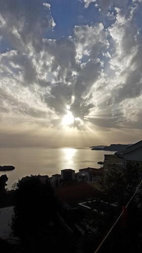 a view of the sun setting over the water at Apartmani Famelja Jovanovic in Sveti Stefan