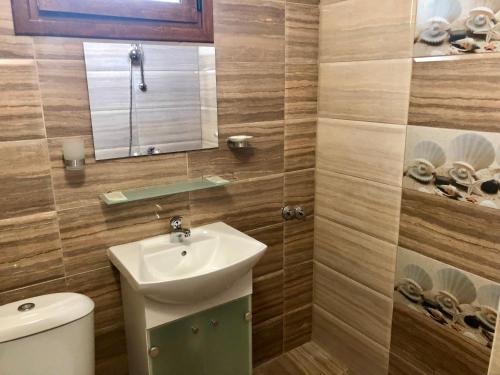 a bathroom with a sink and a toilet and a mirror at Джорджия in Kiten