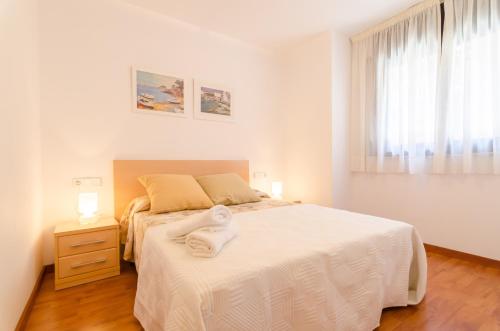 a white bedroom with a large bed and a window at 3 Coronas 1 in Lloret de Mar