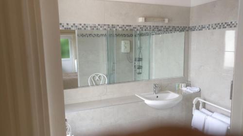 Baño blanco con lavabo y espejo en Rocklands House Bed and Breakfast, en Kinsale