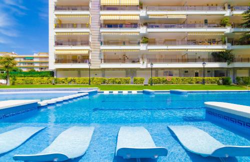 a swimming pool with lounge chairs in front of a building at Alva Park in Lloret de Mar