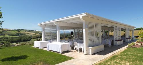 a pavilion with white tables and chairs on a lawn at villa Resort Tre Castelli in Trecastelli