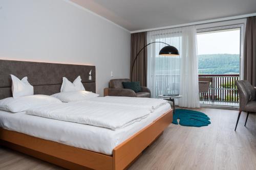 a bedroom with a large bed and a balcony at Seehotel Vinzenz in Velden am Wörthersee