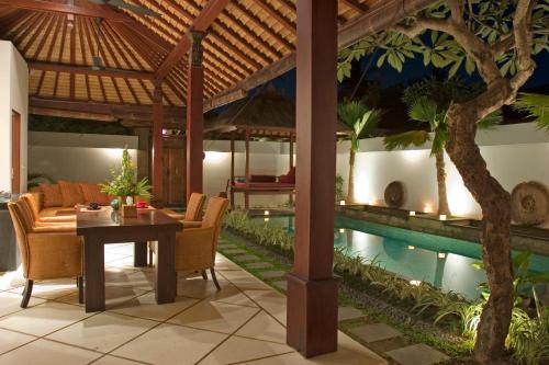 a living room with a table and a swimming pool at Ellora Villa in Sanur