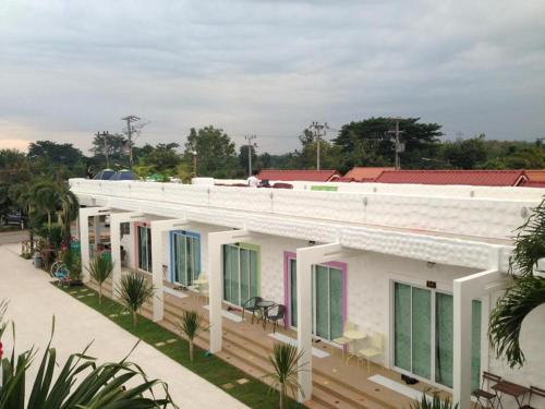 a white building with colorful windows on a street at BaanChomJan @ Suanphung in Suan Phung