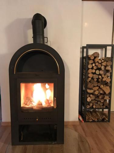 a fireplace with a fire in it next to a pile of logs at Chata na Cihelně in Nové Město na Moravě