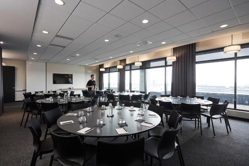 a man standing in a room with tables and chairs at Hôtel Escad Quartier DIX30 in Brossard