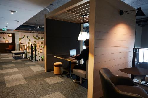 a person sitting at a desk with a laptop at Hôtel Escad Quartier DIX30 in Brossard